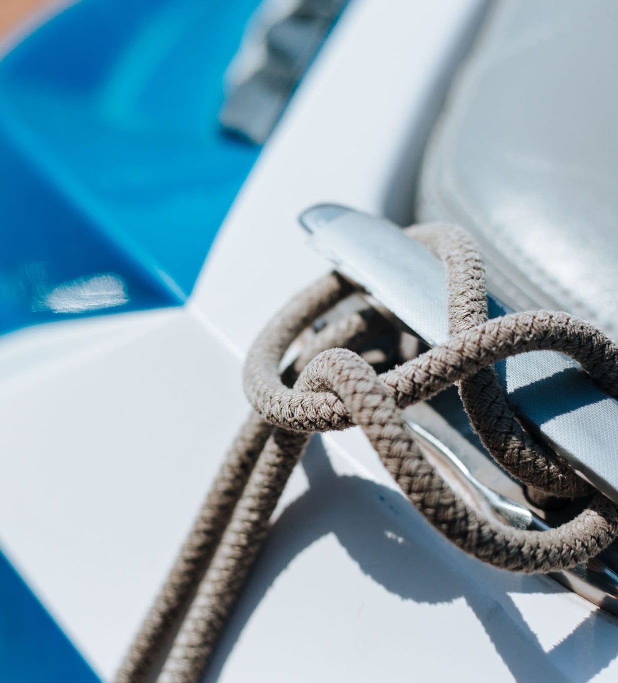 A dock line tied off on the cleat of a white and blue boat